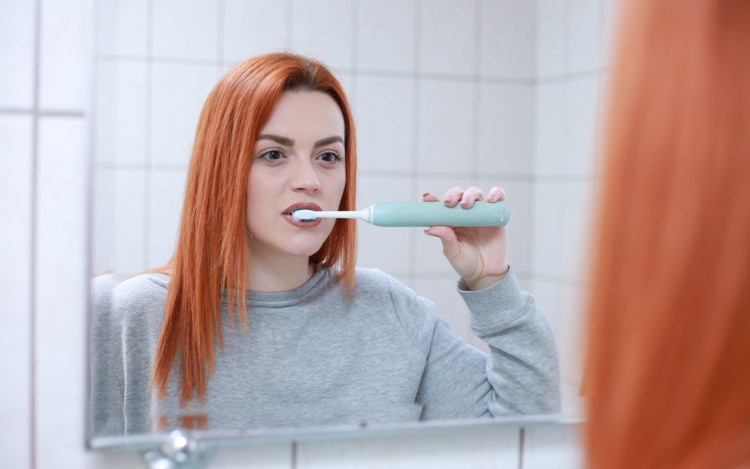 Women brushing teeth in facing mirror